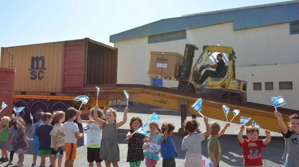 ילדי גן עופרים מקיבוץ שדה בוקר וברקע המכולה הנשלחת לדובאי.